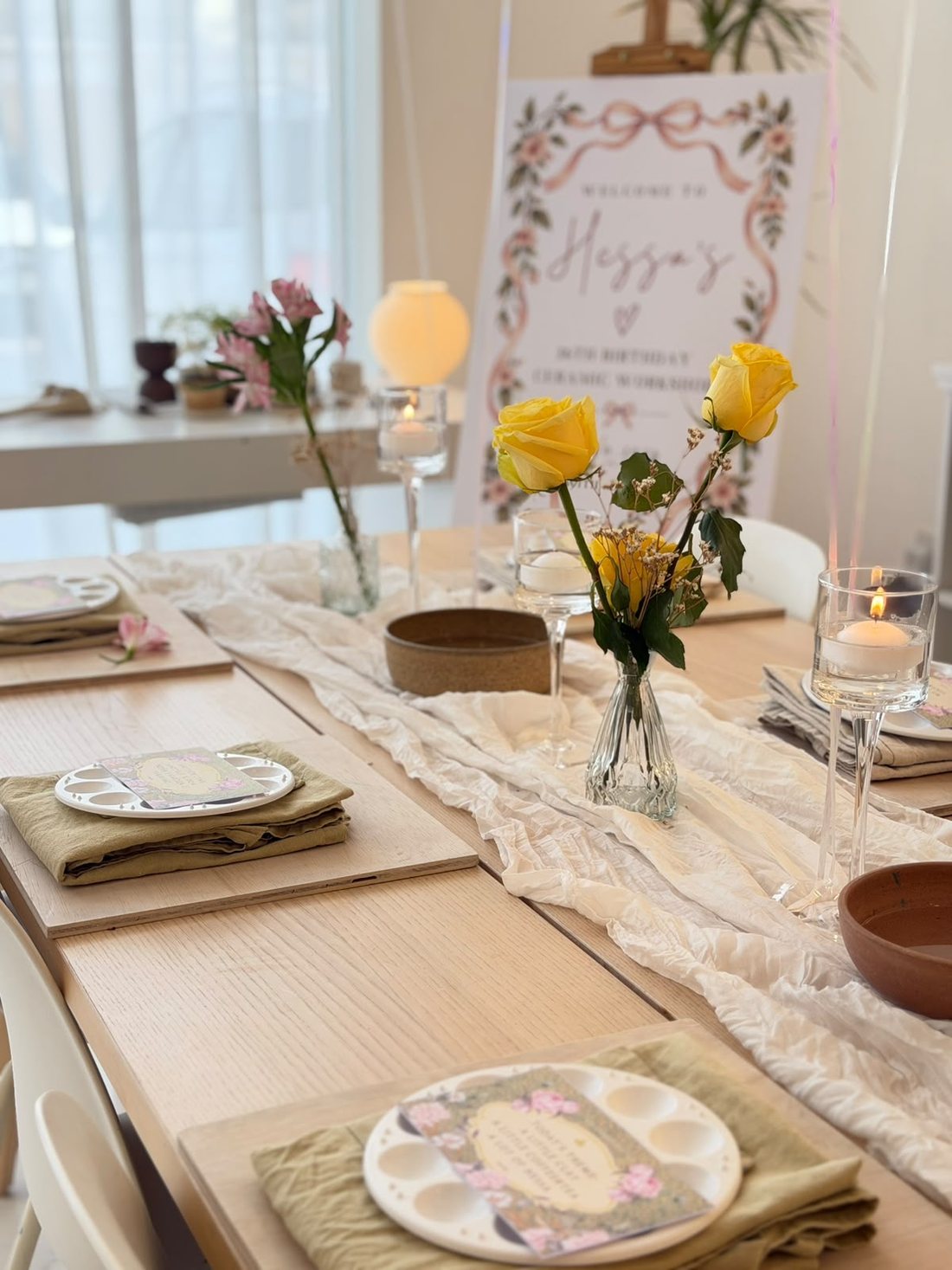 A long table at ROA Art set with yellow roses, floating candles and painting palettes